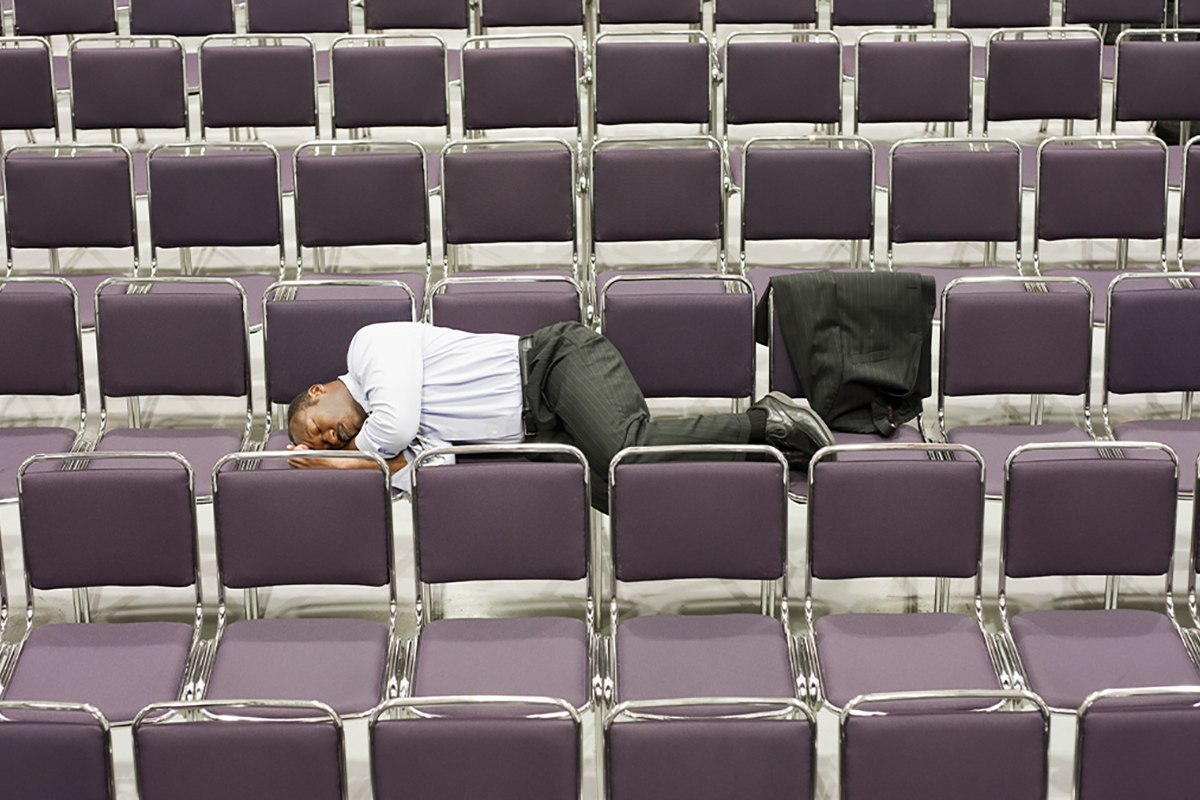 Man in business suit laying in empty chairs