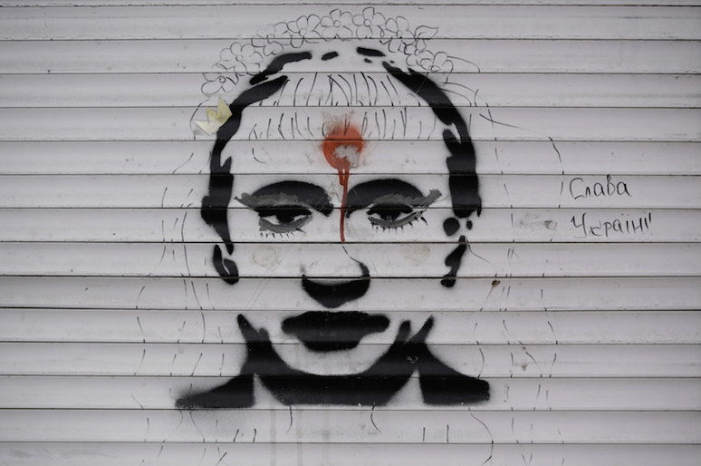 Graffiti depicting Russian President Vladimir Putin and the words “Glory to Ukraine” are painted on the blinds of a battle-damaged shop in Stoyanka, Ukraine, on Sunday. (Vadim Ghirda/AP)