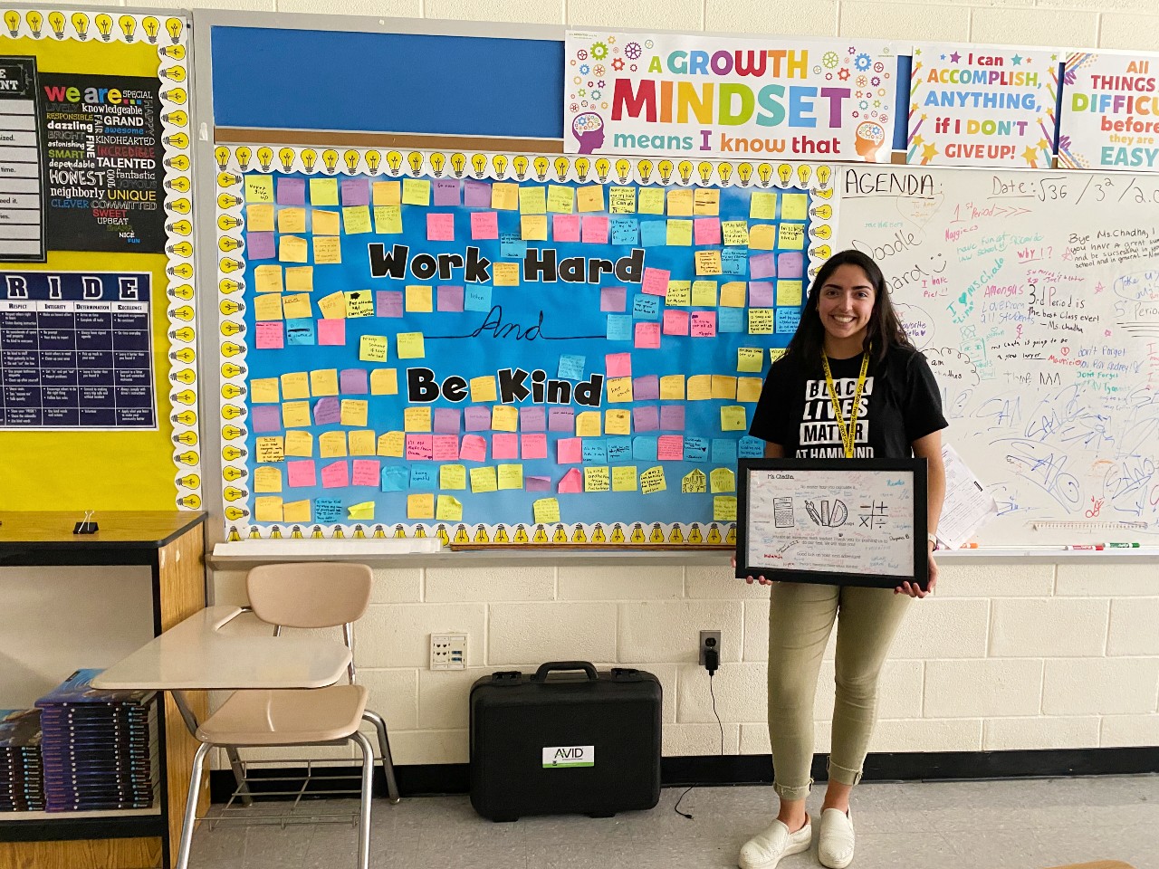 Asha in front of classroom bulletin board