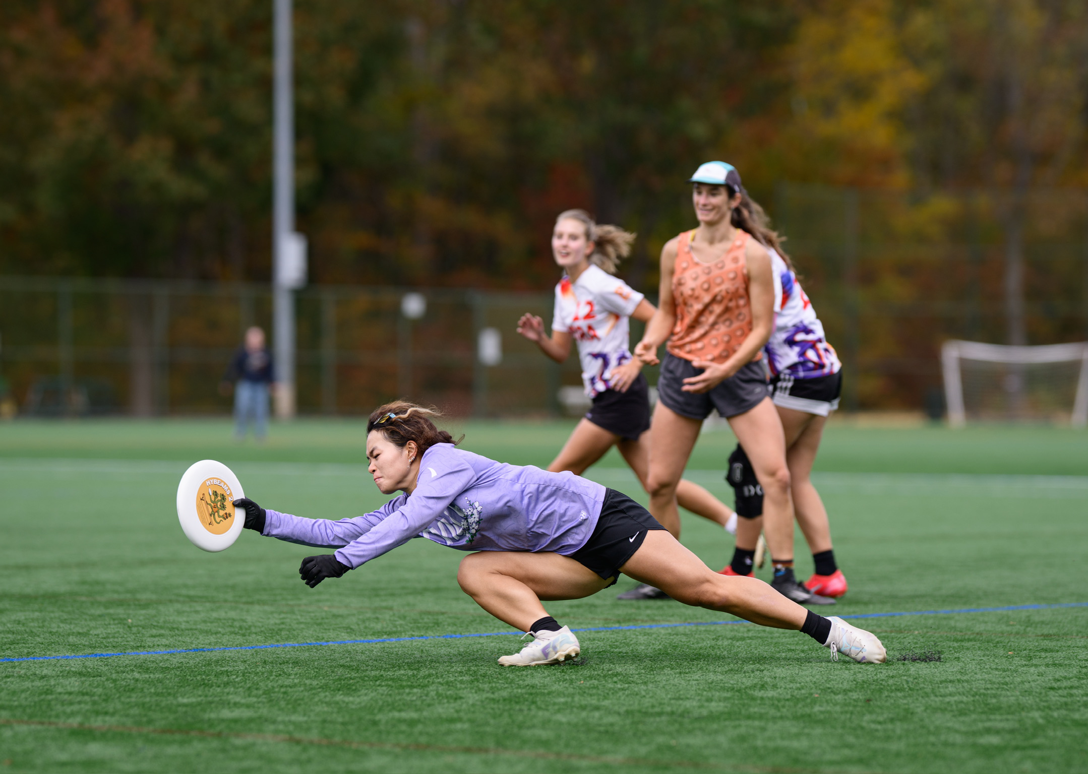 Women's ultimate frisbee player on the field laying out for a grab during a competition