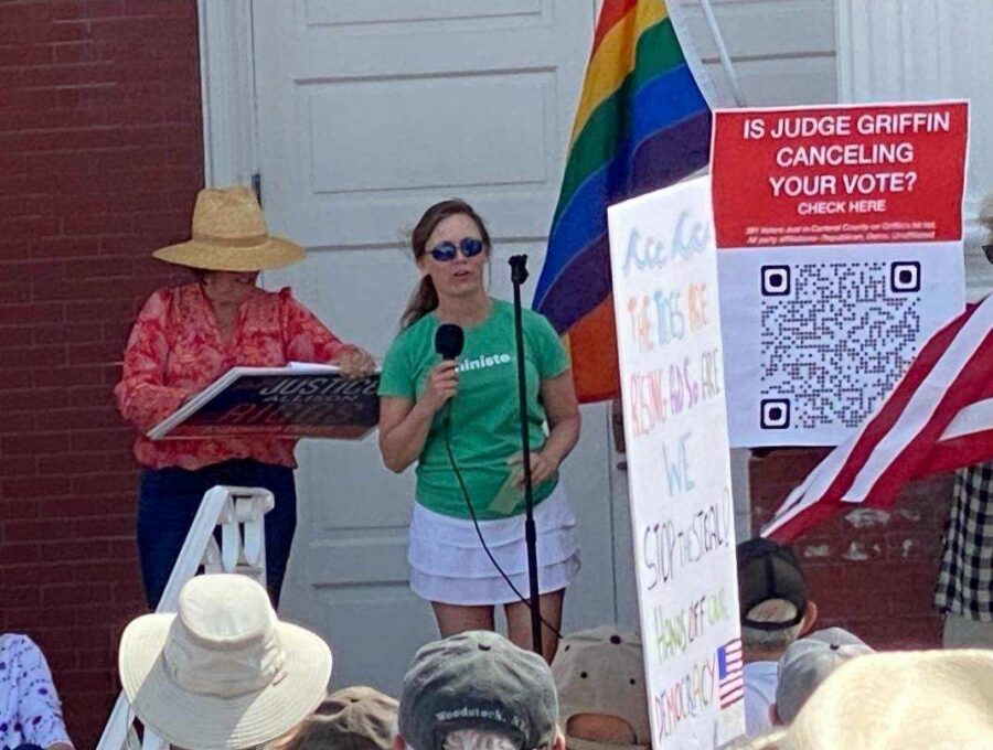 A woman holds a microphone at a community protest event